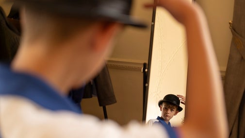 A boy looking in the mirror at Tranmer House, holding an archaeologist's bowler hat on his head